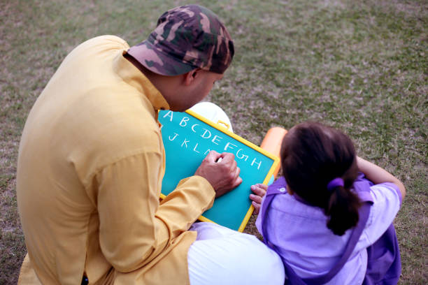Father teaching his cute daughter outdoors in the public park after school.
