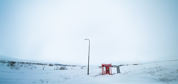 Exterior electric car charger station with a red roof completely surrounded by snow at a service station in Iceland