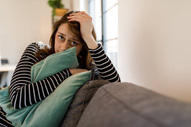 istock Worried young woman embracing a pillow while anxious, looking at camera 1497589767