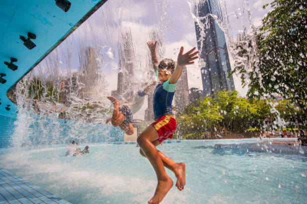 Boys jumping and enjoying in pool that is in front of Petronas Twin Towers of Kuala Lumpur, Malaysia.