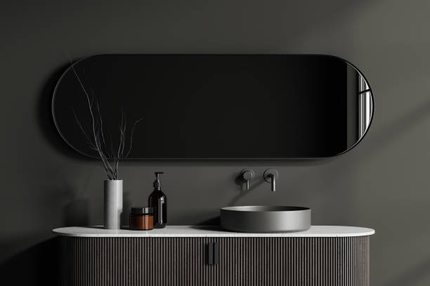 istock Dark bathroom interior with sink and long oval mirror, accessories on deck 1497590798