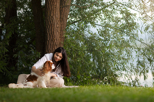 Young woman relaxing on lakeshore with her dog