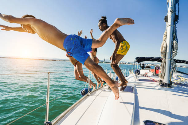 istock Happy friends diving from sailing boat into the sea - Soft focus on front guy face 1497593112