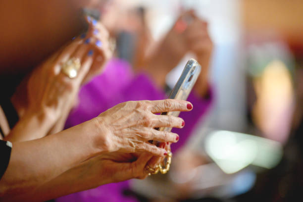Unrecognizable mature woman filming fashion show using smart phone