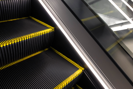 Close-up empty steps of escalator with yellow line, copy space