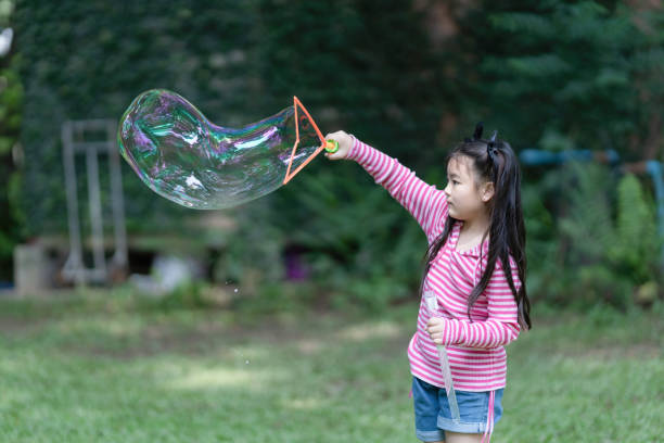 istock Asian girl playing with a bubble machine. 1497595620