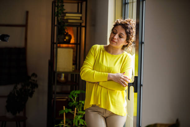 istock Sad woman standing by the window, contemplating her problems away 1497596104