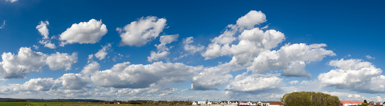 Panoramic photo of white source or fair weather clouds at horizoint against blue sky