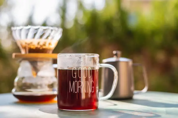 Photo of Hot drip coffee in glass coffee cup with morning sunlight.