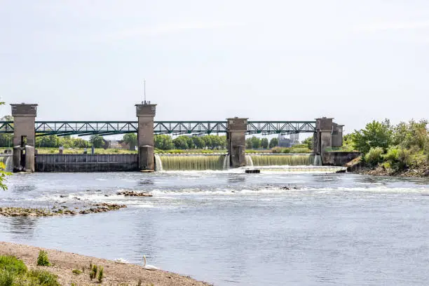 Water flowing in Borgharen dam and lock complex, waterworks to regulate river Maas, concrete pillar towers, steel gates in middle and working steel bridge on top, South Limburg in the Netherlands