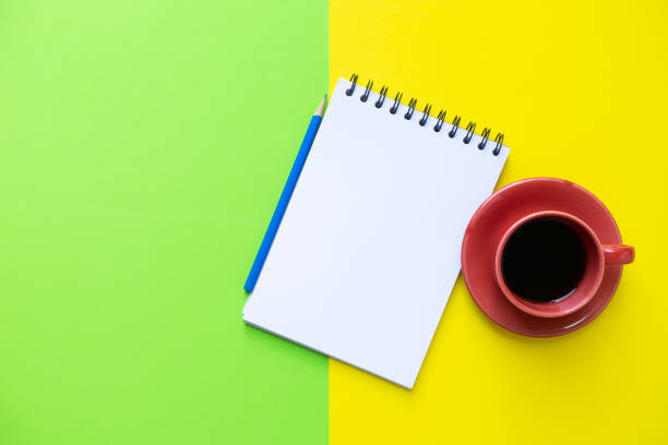 istock Coffee cup, note book on the yellow and green table background, creative at the office 1497604602