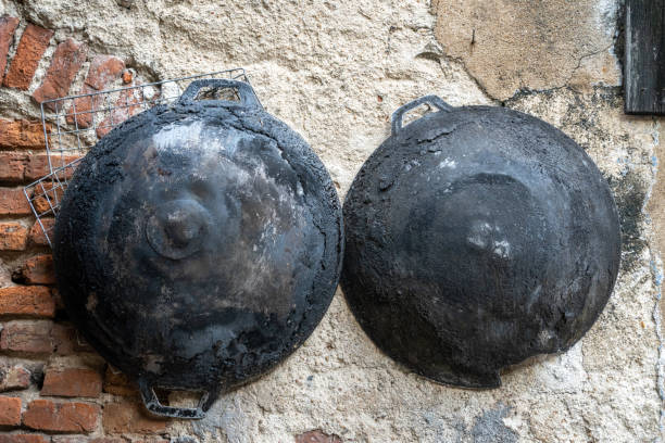 Old frying pans hang on the old cement wall.