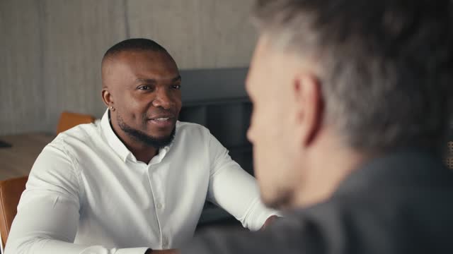 Global Business Partnership: Dialogue and Handshake Between European person and Black person in an Office Setting - Close-up Perspective