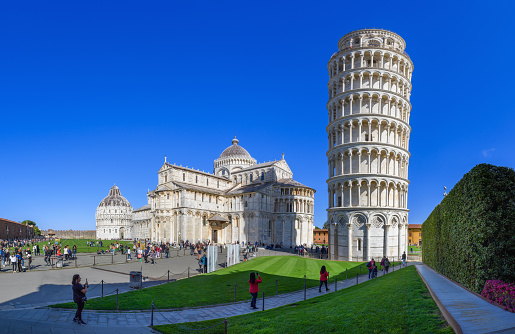 Pisa, Italy - April 2, 2023: The Cathedral and the Leaning Tower of Pisa on a bright summer day against the blue sky. Tuscany, Italy