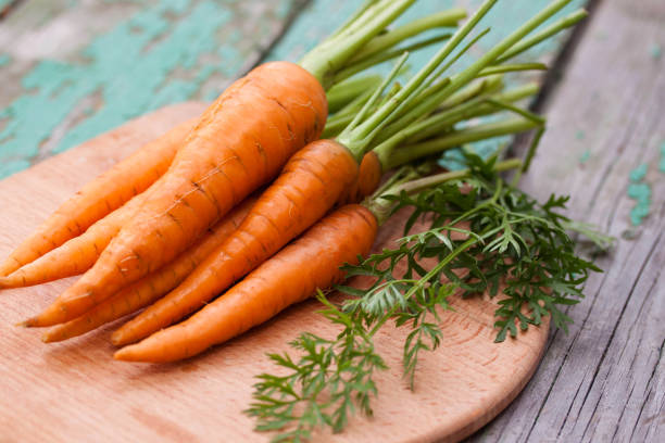 istock Fresh carrots with greens on a wooden board 1497616819