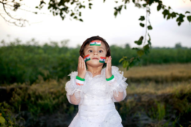 2-3 years girl standing against nature background outdoors in the agricultural field with tricolor on both cheeks.