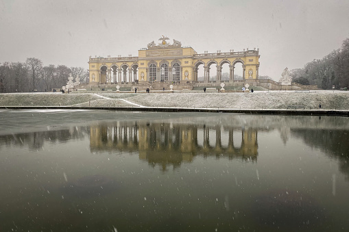 Vienna, Austria - January 18, 2020: The Glorietta at Schönbrunn Palace Park in winter during snowfall against cloudy sky