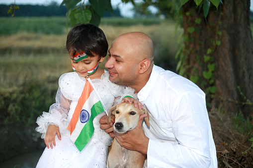 Father and his cute baby daughter celebrating Independence day outdoors  in agricultural field.