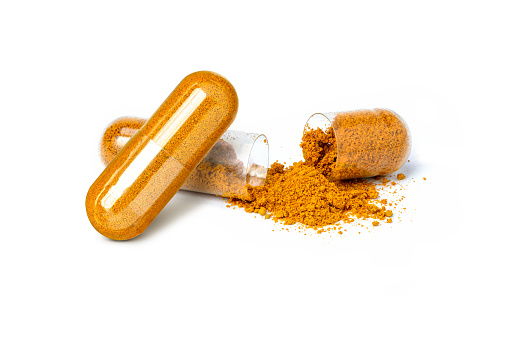 Closeup turmeric herbal powder capsules isolated on white background.