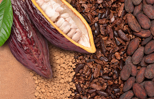 Fresh cocoa fruit with beans on chocolate ingredients (cocoa nibs, cocoa mass and cacao powder) texture background, Chocolate ingredients concept. Top view, flat lay.
