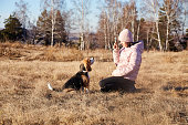 A girl on a walk trains her dog beagle. Autumn landscape.