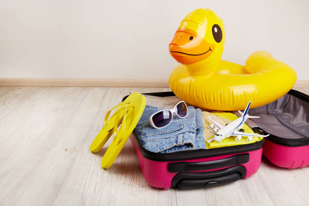 Suitcase with clothes and leisure accessories. Summer travel, preparation for the trip Suitcase with clothes and leisure accessories. Summer travel, preparation for the trip, packing of luggage. duck inflatable ring inflatable swimming pool stock pictures, royalty-free photos & images
