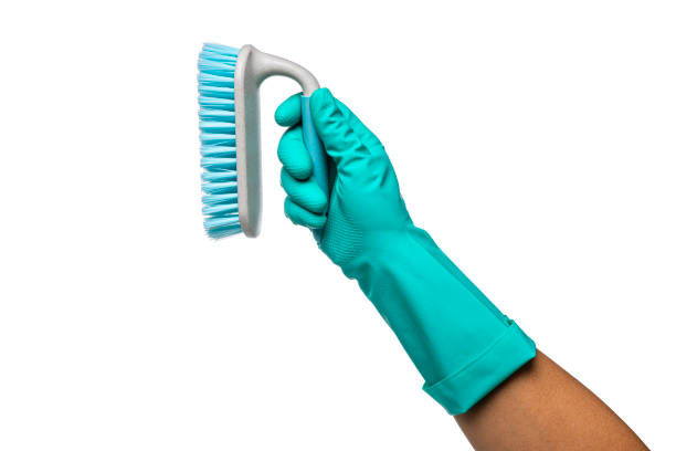Hand wearing washing glove holds scrubbing brush
