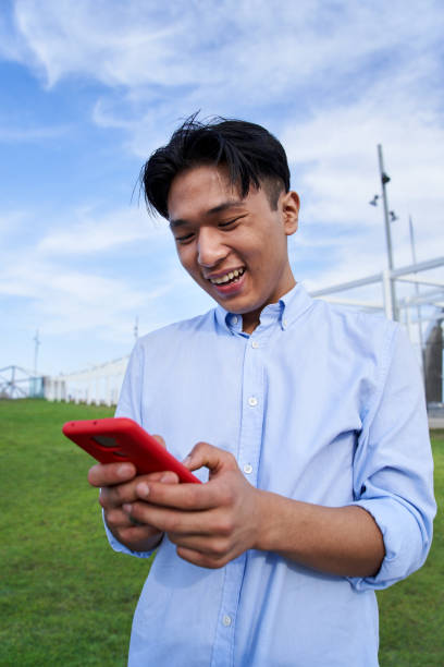 istock Vertical happy Asian boy using phone and smiling with positive attitude. Young man social networks. 1497628259