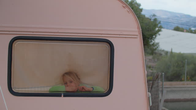 Little Blonde Girl Peeking Out of Camper Van Window