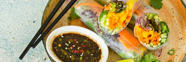 istock Fresh Asian appetizer Spring rolls (Nem) made from rice paper and raw vegetables and herbs with hot sauce on a light blue background. 1497629589
