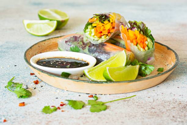 istock Fresh Asian appetizer Spring rolls (Nem) made from rice paper and raw vegetables and herbs with hot sauce on a light blue background. 1497629590