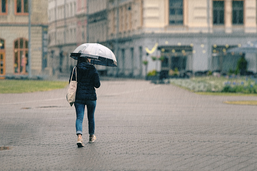 a woman with a transparent umbrella walks through the city on a rainy day.