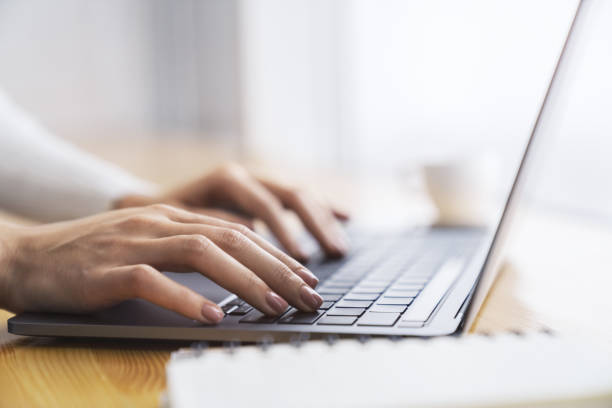 istock Against a blurred office scene, a close-up shot reveals a woman's hands typing on a modern laptop keyboard 1497641751