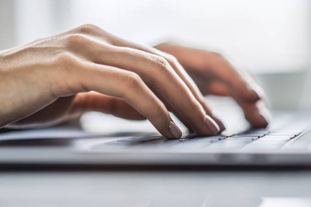 istock Office environment softly blurred behind, the image focuses on a woman's hands typing on a chic laptop keyboard 1497642234