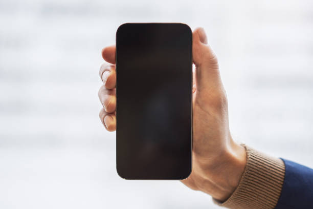 istock Male hand holding modern smartphone with blank screen on blur background, mockup, closeup 1497643544
