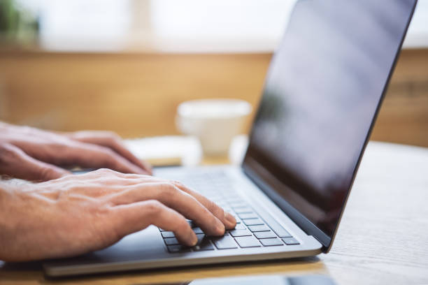 istock With an office backdrop appearing blurry, a close-up presents a man's hands typing on a state-of-the-art laptop keyboard 1497643597