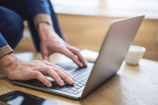 istock Set against a blurry office backdrop, the image captures a man's hands in close detail, typing on a cutting-edge laptop keyboard 1497643606