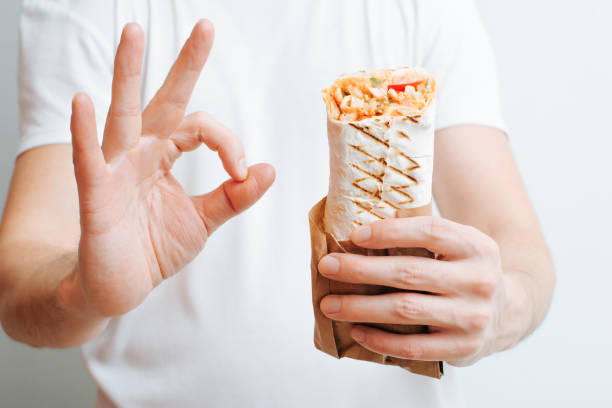 Close-up caucasian man holding shawarma, kebab or doner and showing ok gesture stock photo