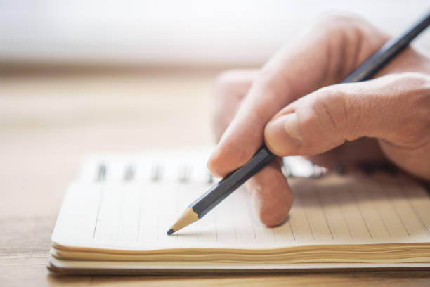 istock Close-up depiction of a man's hand taking notes in a notepad, with a blurred background 1497643782