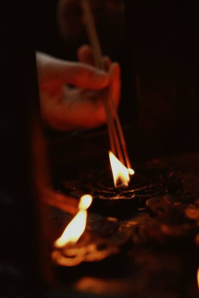 istock Person is ceremoniously lighting incense sticks over water in a dimly lit space 1497649857