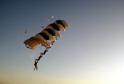 Army Paratrooper with yellow  parachute open and American flag flapping in the wind. Photo taken in non ticket area Miramar Airbase in San Diego California USA on September 23, 2022.