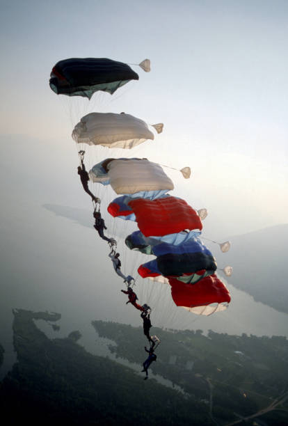 skydive athletes perform above swiss mountain landscape - mountain drop europe switzerland imagens e fotografias de stock