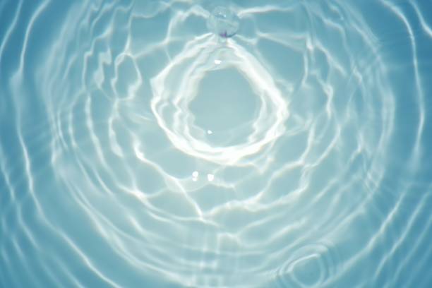 Blue water with ripples on the surface. Defocus blurred transparent blue colored clear calm water surface texture with splashes and bubbles. Water waves with shining pattern texture background.