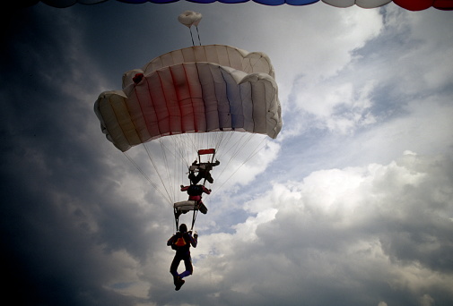 parasail with two swimmers hanging  being pulled by a motor boat