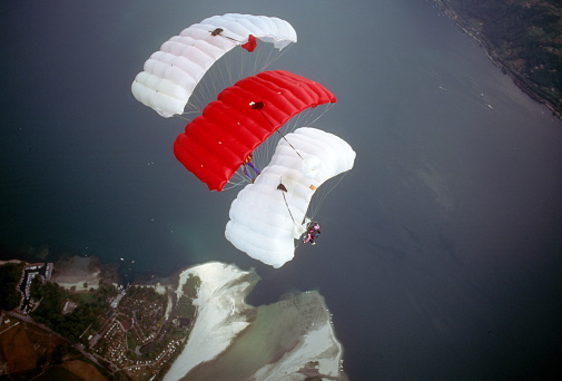 A large parachute with two girls flies in the air over the sea.\