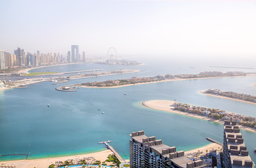 Dubai, UAE - August 28, 2022:  Beaches and Dubai eye view at sunset with boats and yachts in the Persian gulf waters. Panoramic view at Dubai Marina