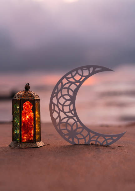 istock Eid Mubarak background, half moon shape with colourful lantern lamp in the beach 1497659681