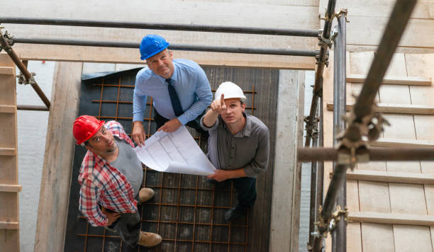 Architect And Two Construction Workers On A Construction Site stock photo