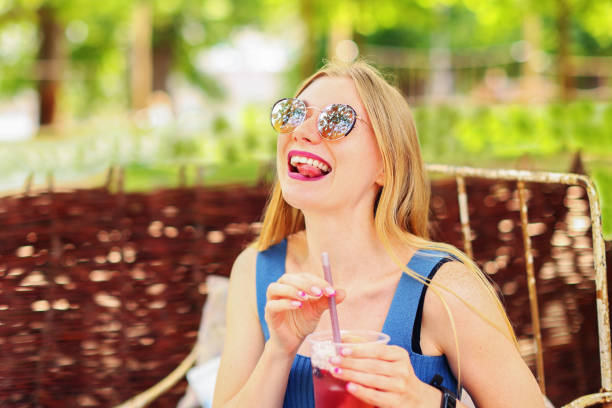 girl drinks lemonade from a plast glass, make fun and show language