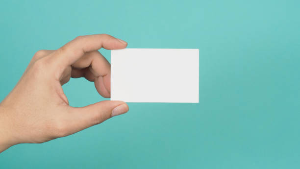 istock Hand holding white blank card isolated on mint green or Tiffany Blue background. 1497673821